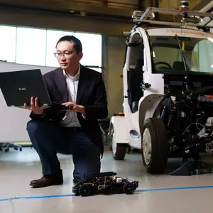 Jun Chen, Ph.D. in a lab with a vehicle.