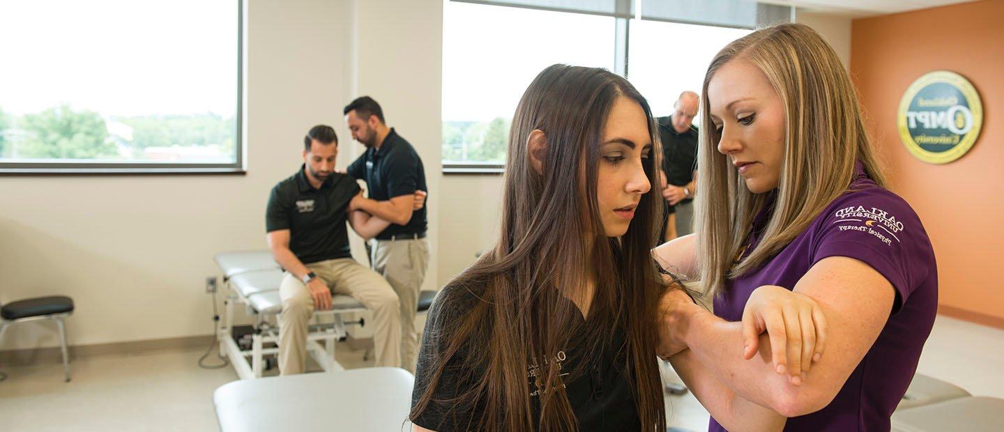 physical therapist working on a young woman's shoulder in a clinic