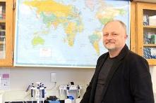 生物学教授Taras Oleksyk站在墙上的地图前.